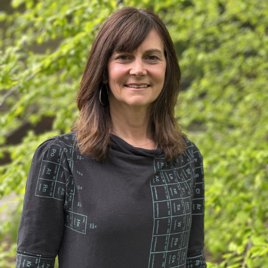 Pharmacist Jennifer Bruce image in front of green bushes.