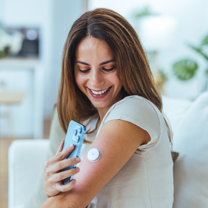 Smiling woman scanning her sensor on her arm with her mobile device.