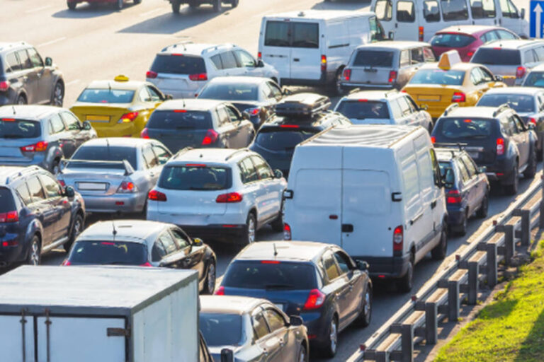 Heavy traffic jam with cars and vans crowded on a multi-lane highway during daytime.