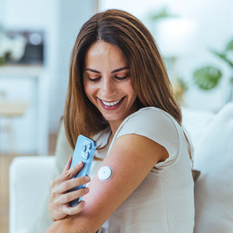 Smiling woman scanning her sensor on her arm with her mobile device.